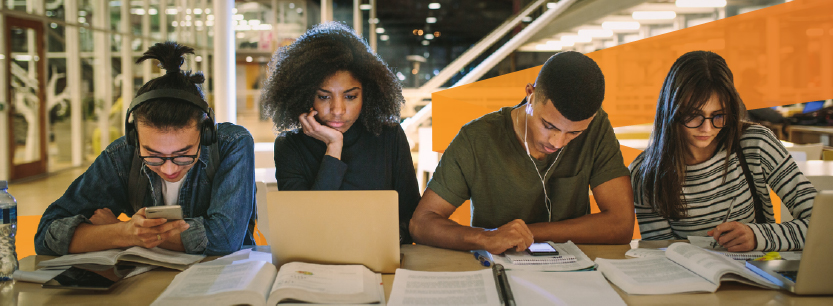 Higher education students studying at a large desk.