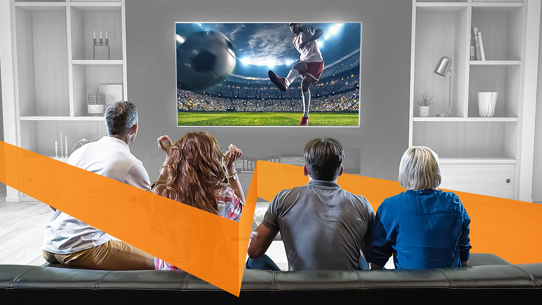 Several people watching a sporting event on a TV in the common area of a multi-dwelling unit