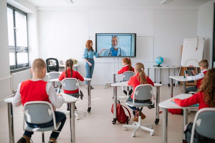 primary ed students watching guest speaker on a tv